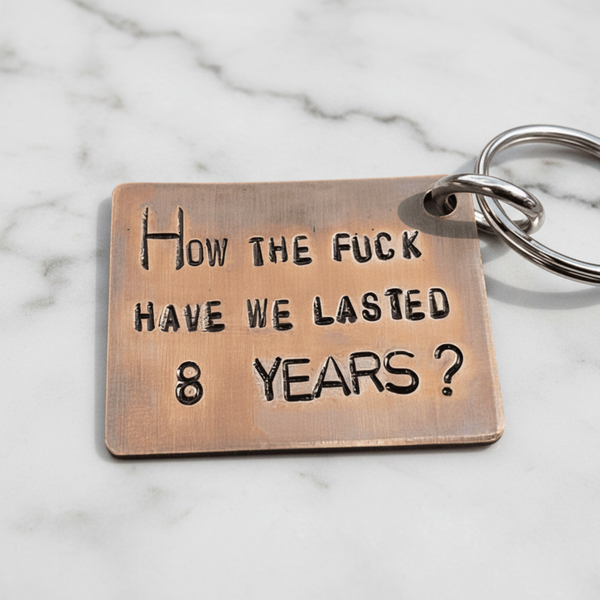 8th Anniversary bronze keychain with the phrase 'How the fuck have we lasted 8 years?' hand stamped design